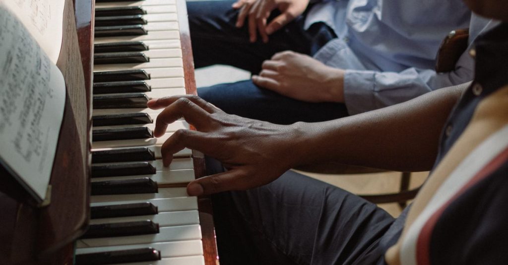 Hands of teacher and student playing piano keys during a private lesson, focusing on musical instruction.
