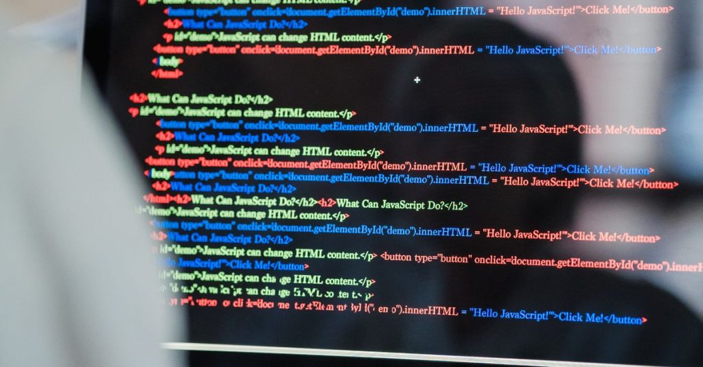 A close-up of a computer screen displaying colorful coding script in an office environment.