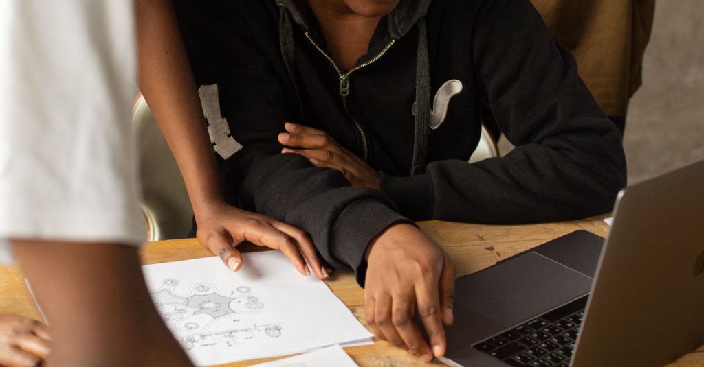 A diverse team working together on a project around a laptop in an office.