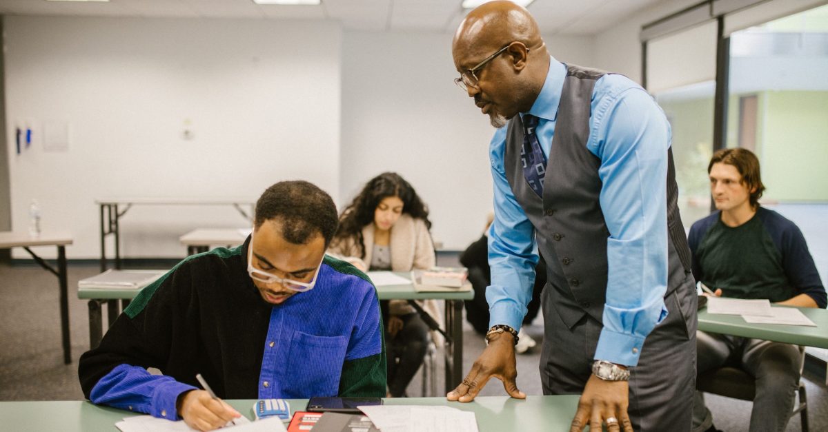 Educator supervising students during a test in a college classroom.